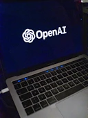 A mentor guiding a young professional through AI project details on a laptop.