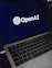 A laptop screen displaying the OpenAI logo and text. The laptop keyboard is visible below, with keys illuminated in a dimly lit environment.