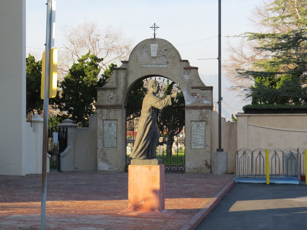 a statue of a woman holding a cross in front of a gate