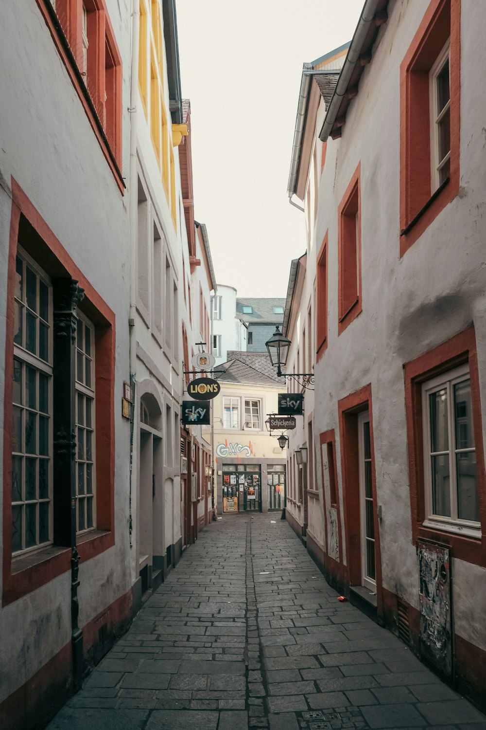 eine Kopfsteinpflasterstraße mit roten Fensterläden und Fenstern