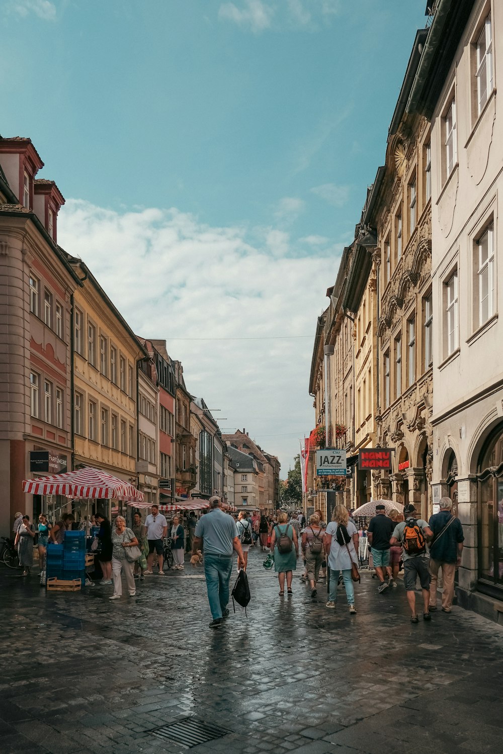 a group of people walking down a street next to tall buildings