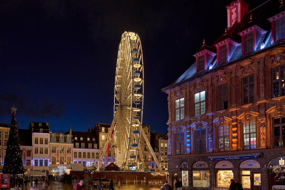 a ferris wheel lit up at night in a city