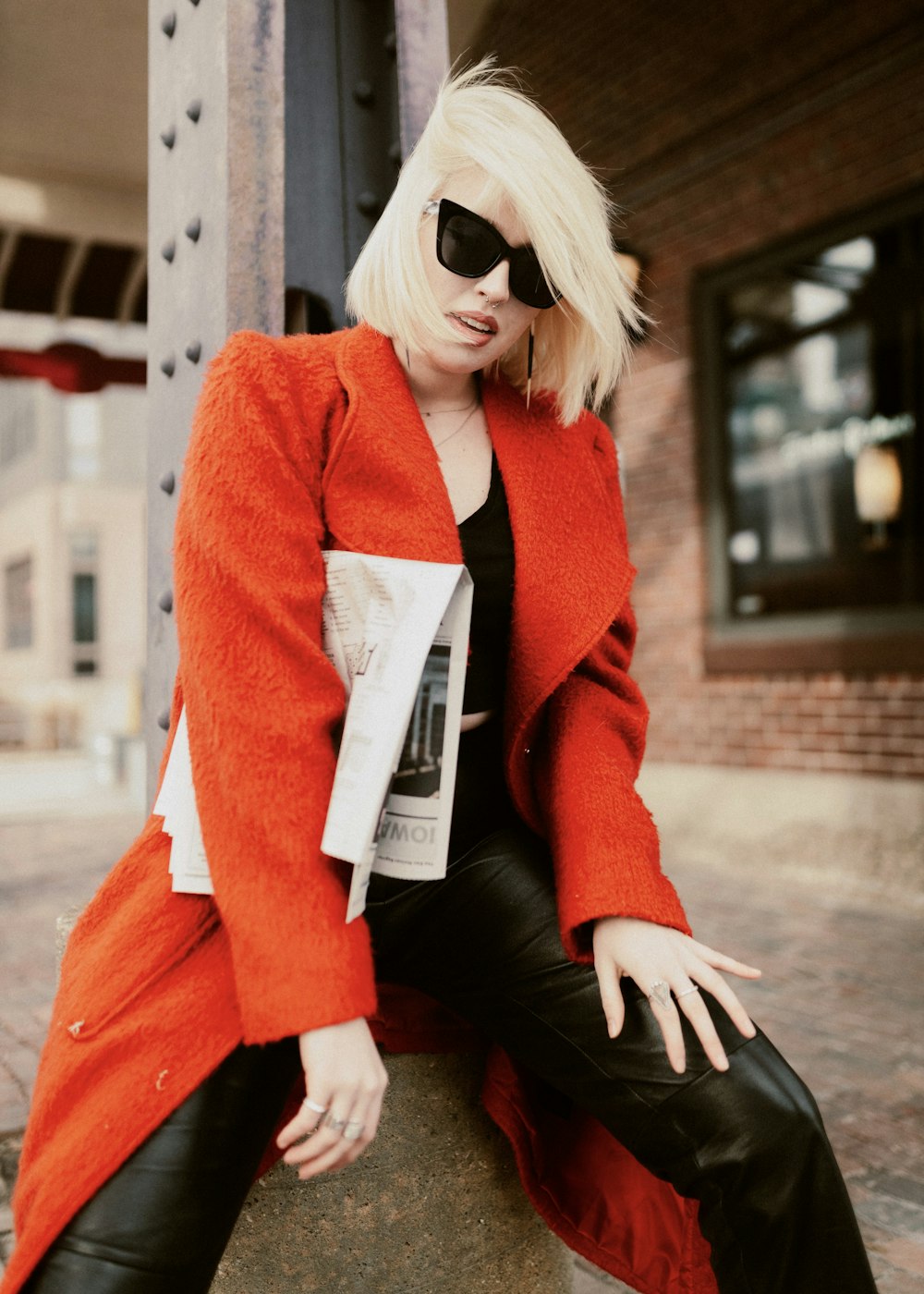 a woman in a red coat sitting on a pole