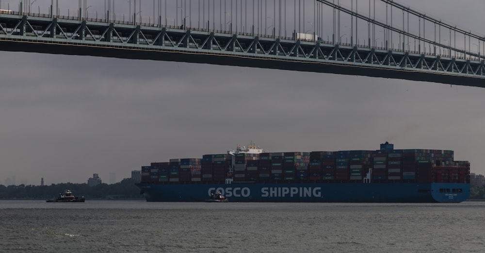 a large cargo ship passing under a bridge