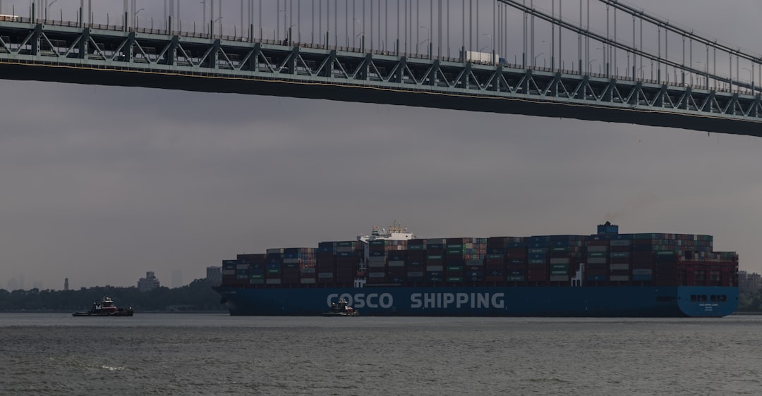 a large cargo ship passing under a bridge,