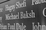 Names are inscribed on a dark, polished surface, likely a memorial or a plaque. The engraved text stands out sharply against the background.