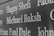 Names are inscribed on a dark, polished surface, likely a memorial or a plaque. The engraved text stands out sharply against the background.