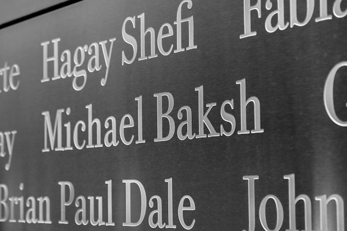 Names are inscribed on a dark, polished surface, likely a memorial or a plaque. The engraved text stands out sharply against the background.
