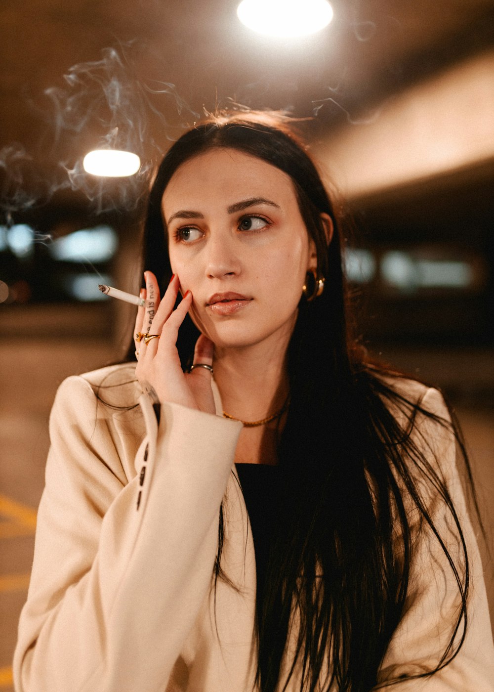a woman smoking a cigarette in a parking lot