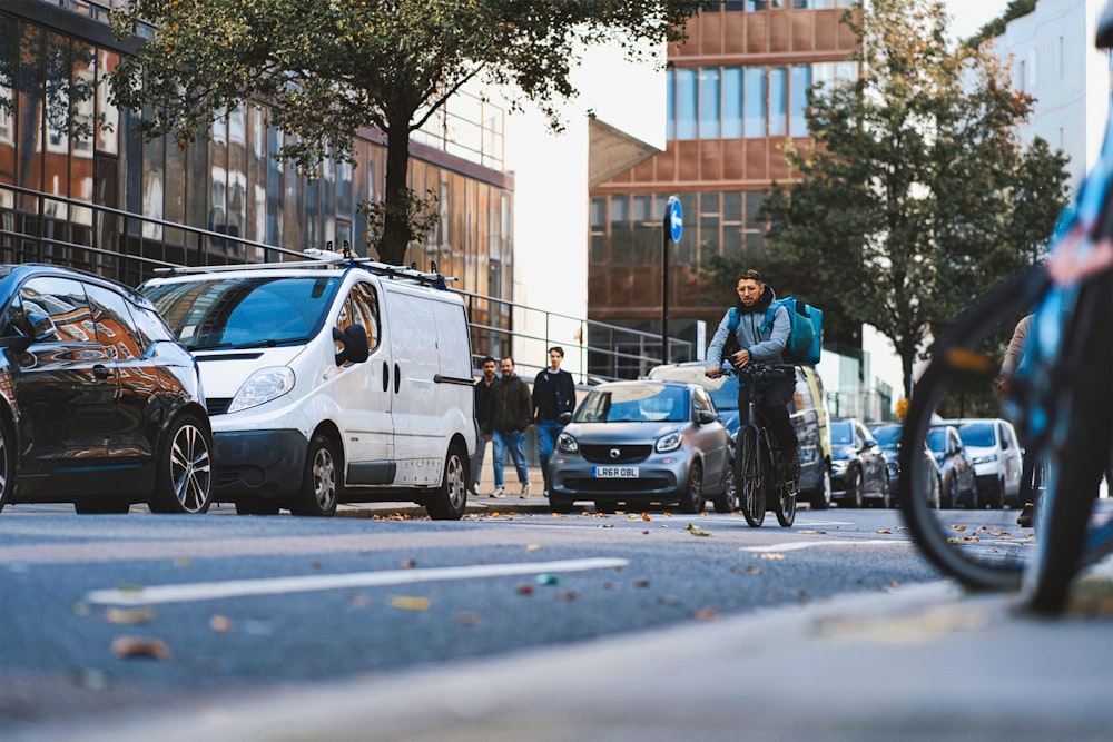 a man riding a bike down a street next to parked cars