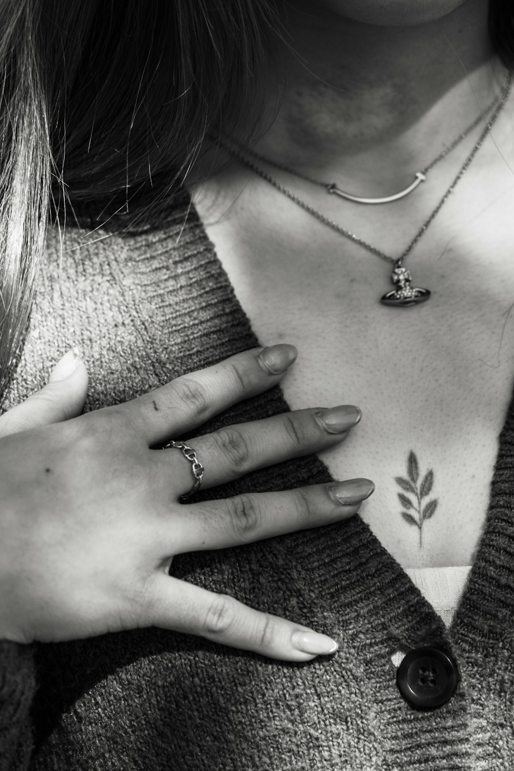 a woman wearing a sweater and holding her hand on her chest