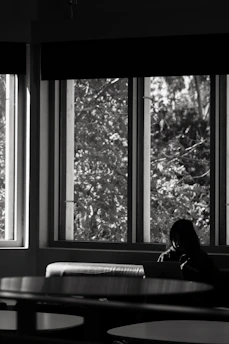 A calm workspace with a person thoughtfully looking at a laptop, sunlight softly illuminating the desk.