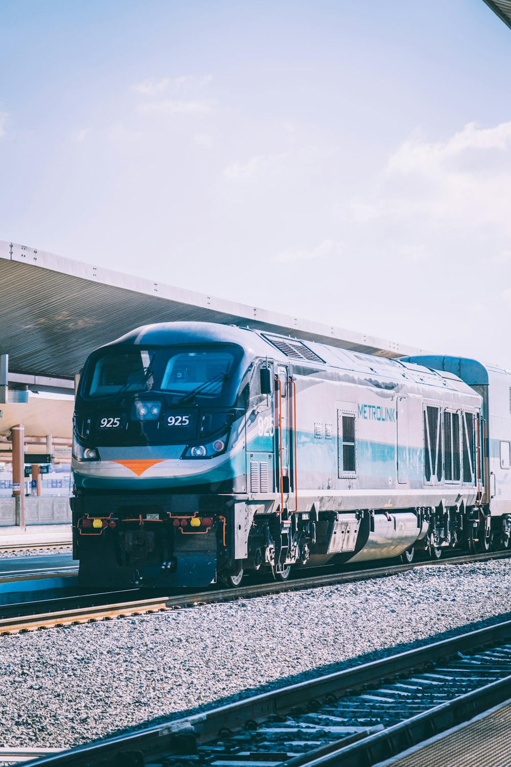 a silver train traveling down train tracks next to a train station