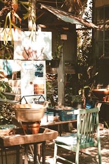 A rustic wooden dining table with mismatched chairs surrounded by potted plants on a rooftop.