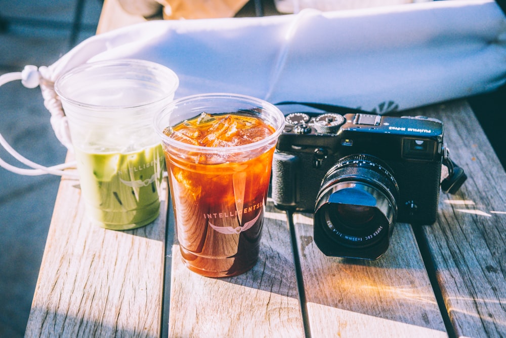 a camera and a drink on a wooden table