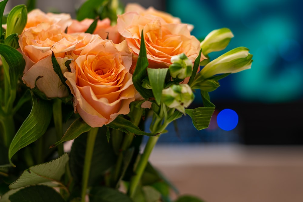 a vase filled with orange roses on top of a table