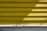 A freshly painted yellow wall with clean edges and a glossy finish in a kitchen