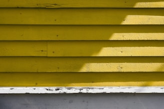 Close-up of a painter carefully applying a smooth coat of yellow paint on a wooden wall