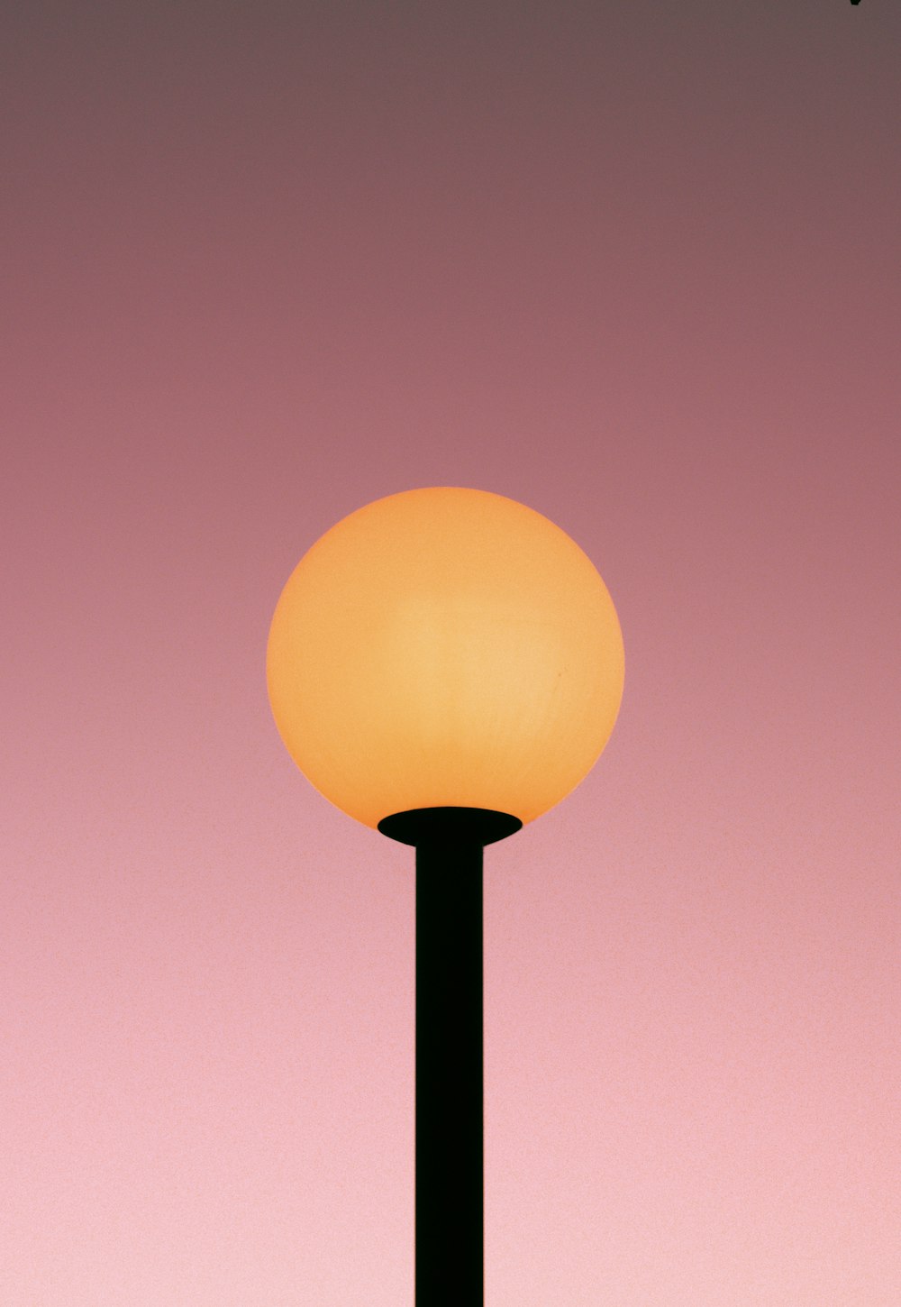 a street light with a pink sky in the background