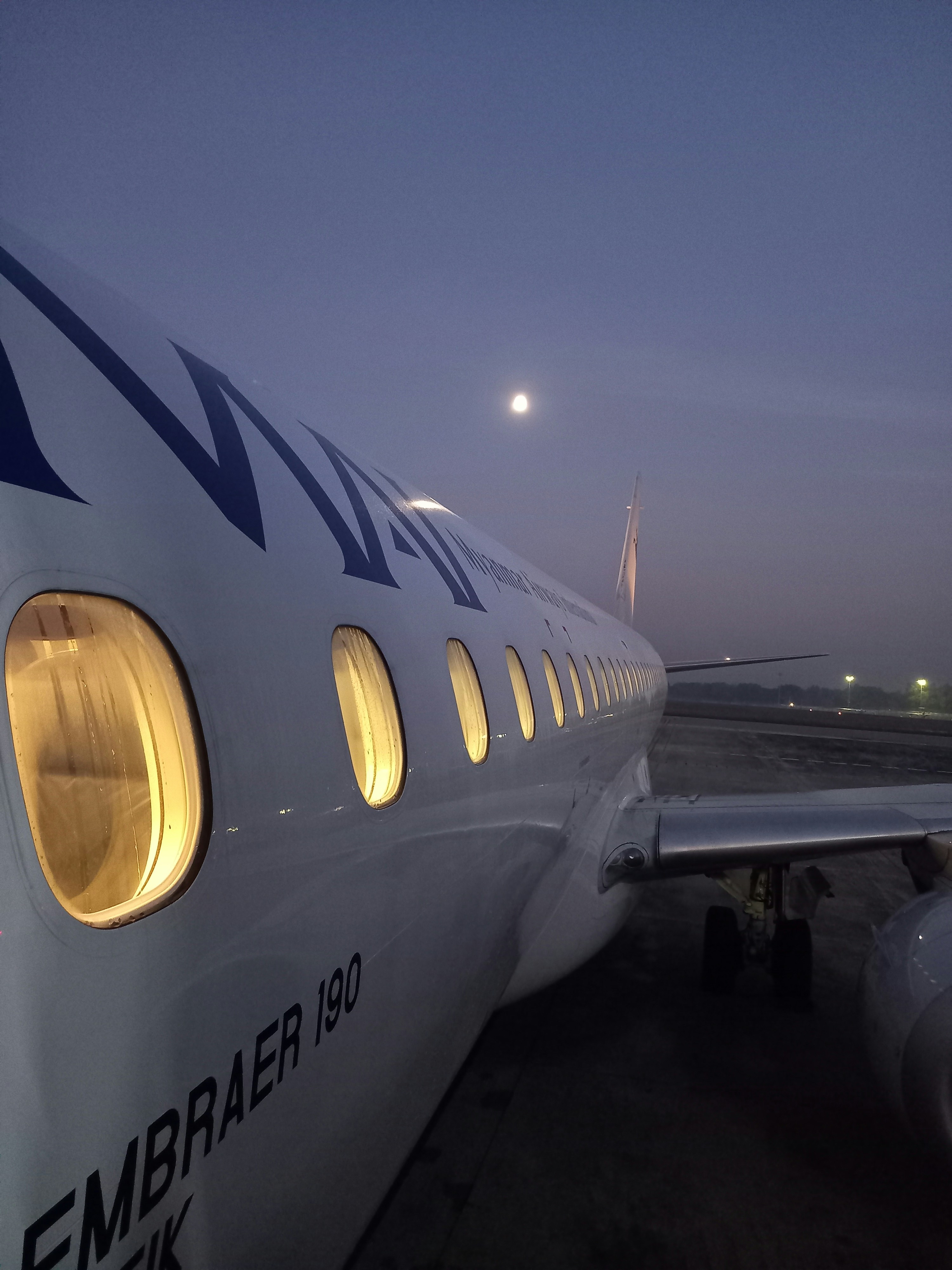 Private aircraft on tarmac at dusk, deep twilight sky, dim runway lights, dark aircraft silhouette, atmospheric low-key aviation scene