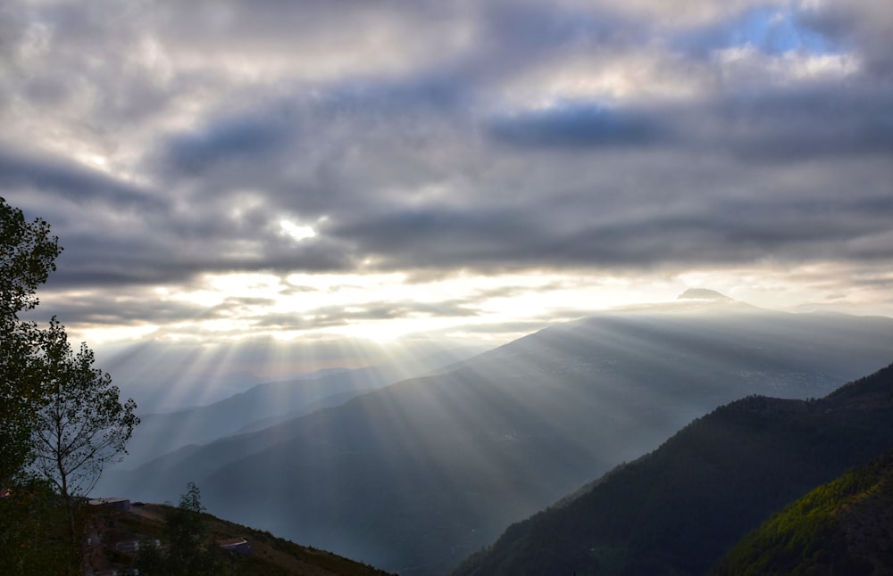 the sun shines through the clouds over the mountains