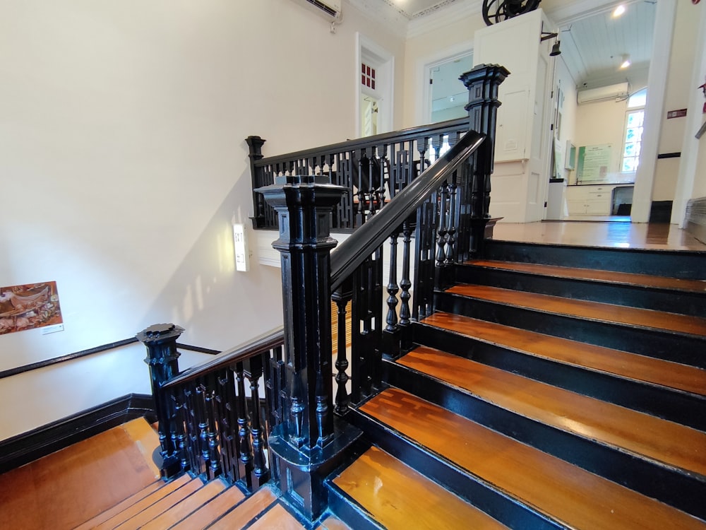 a staircase with black railing and wood floors