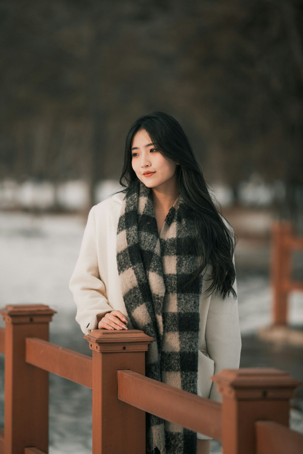 a woman standing on a bridge wearing a scarf