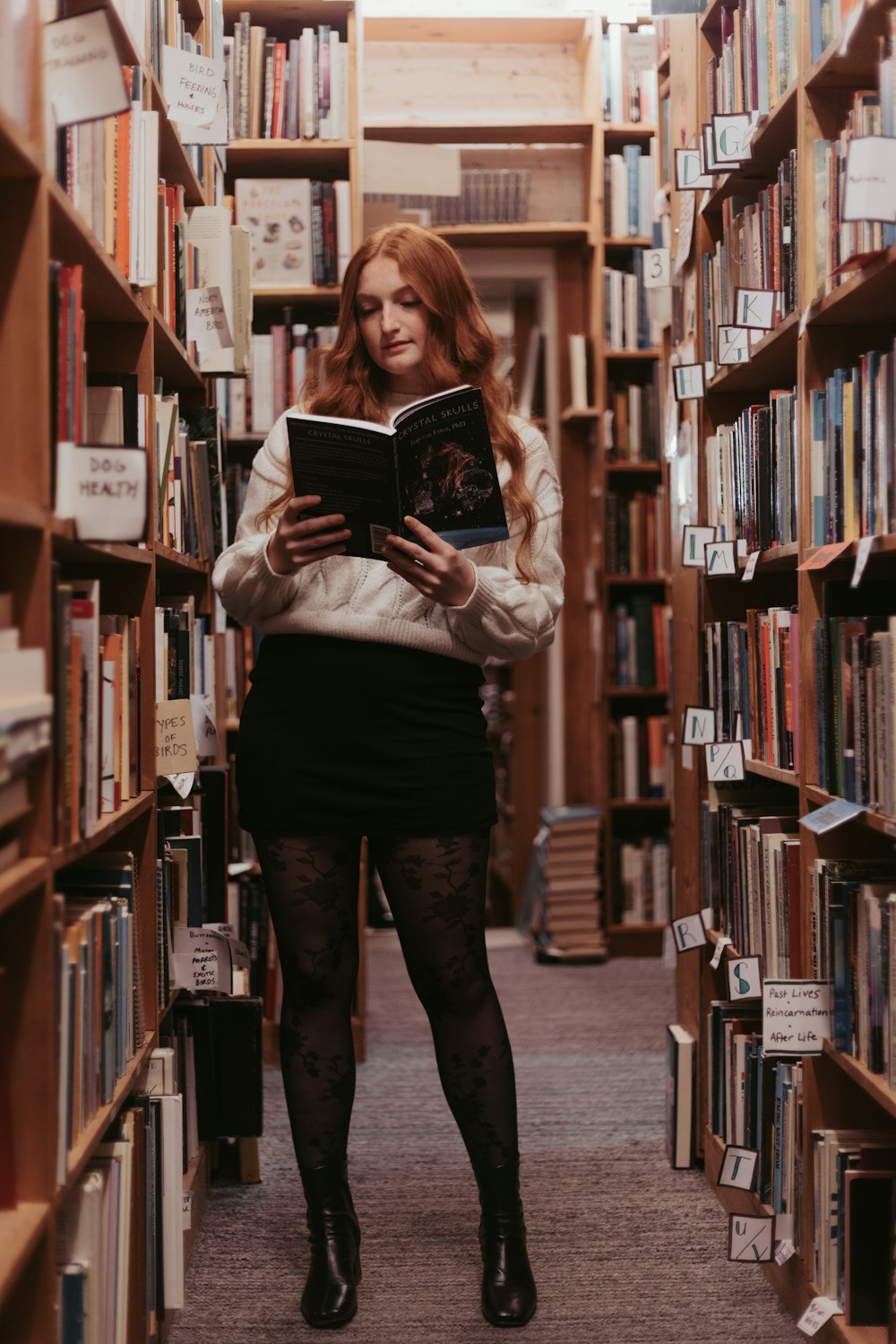 a woman standing in a library holding a book