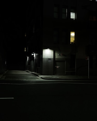 Close-up of a neighborhood street with subtle shadows hinting at someone lurking cautiously.