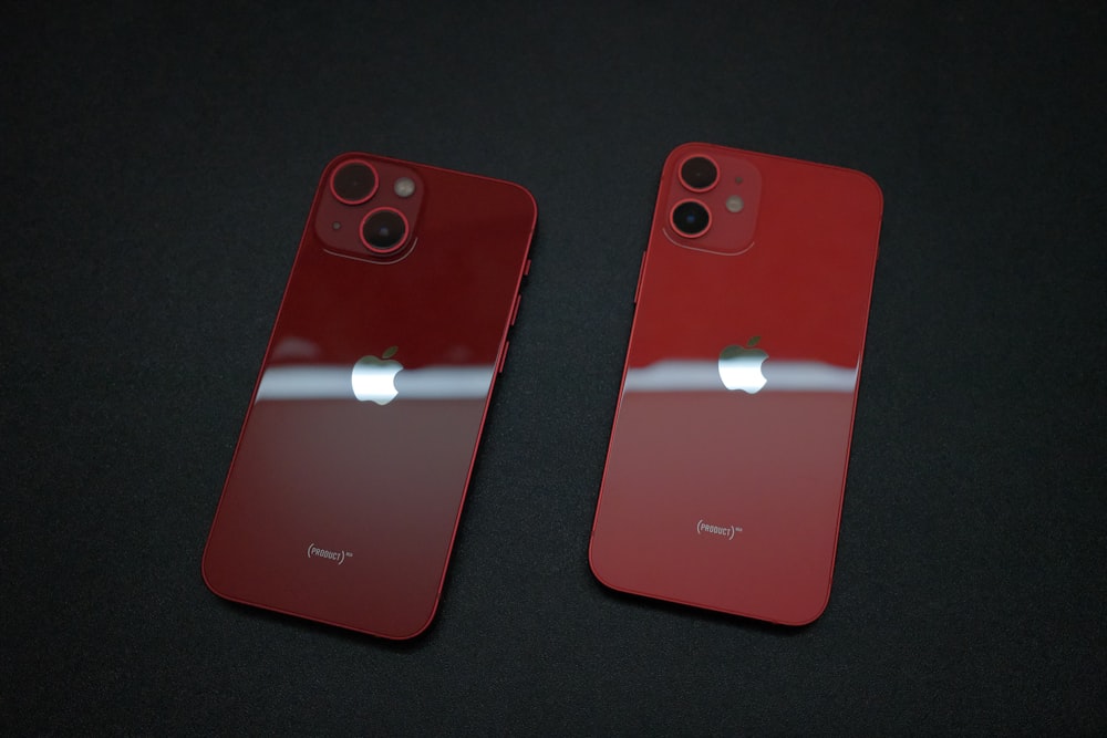 two red iphones side by side on a black surface