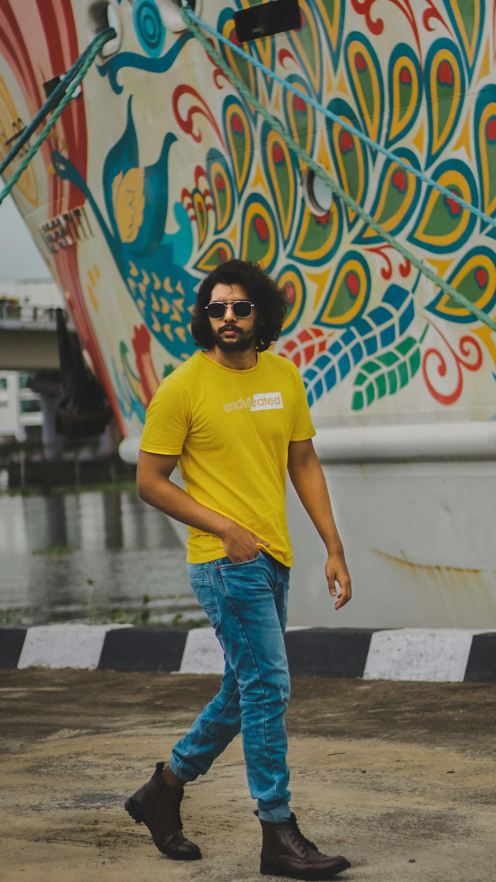 a man in a yellow t - shirt is walking by a boat