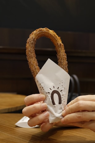 A happy customer enjoying a warm churro on a sunny day.