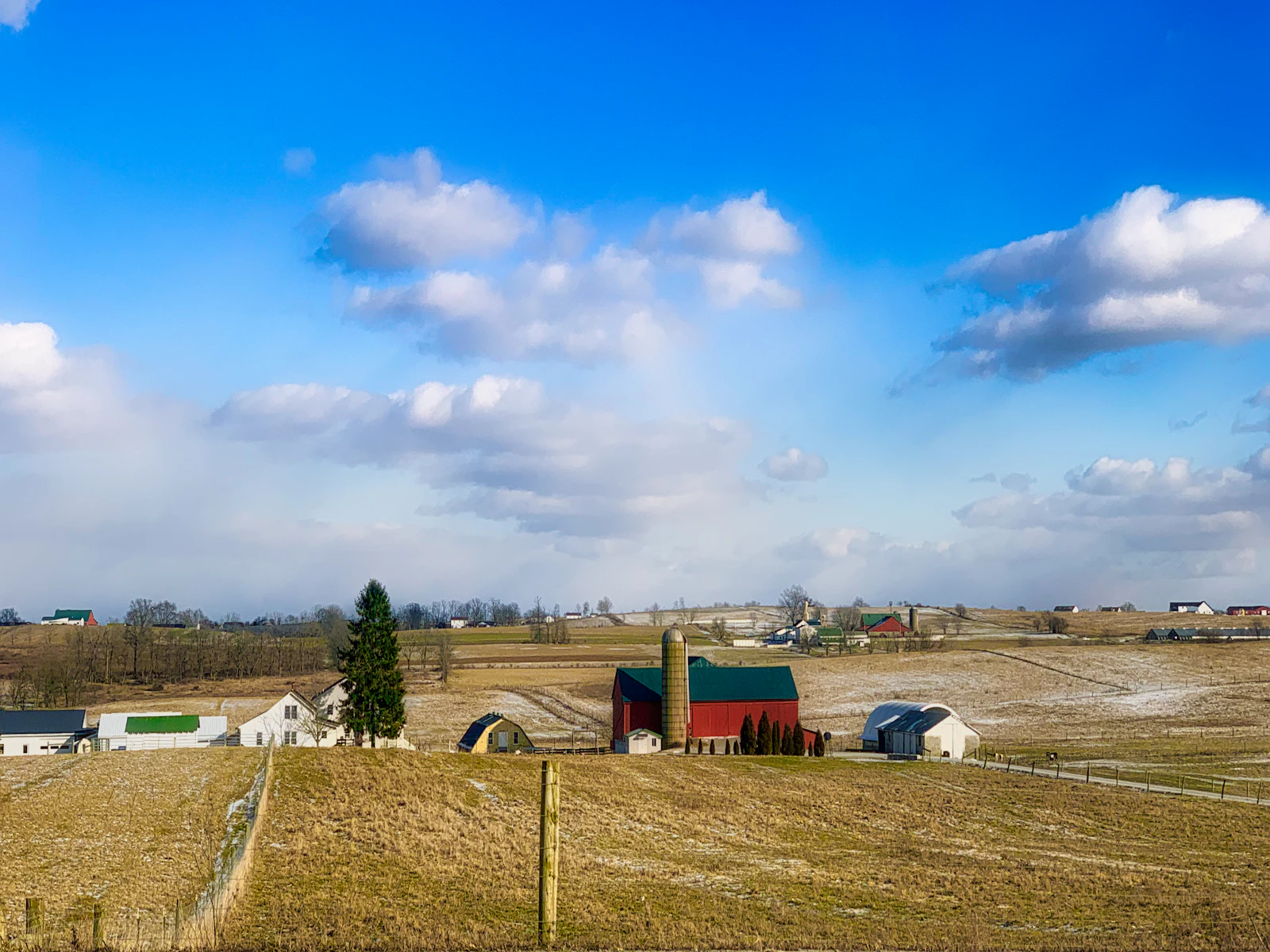 A farmstead and outbuildings under an open sky.