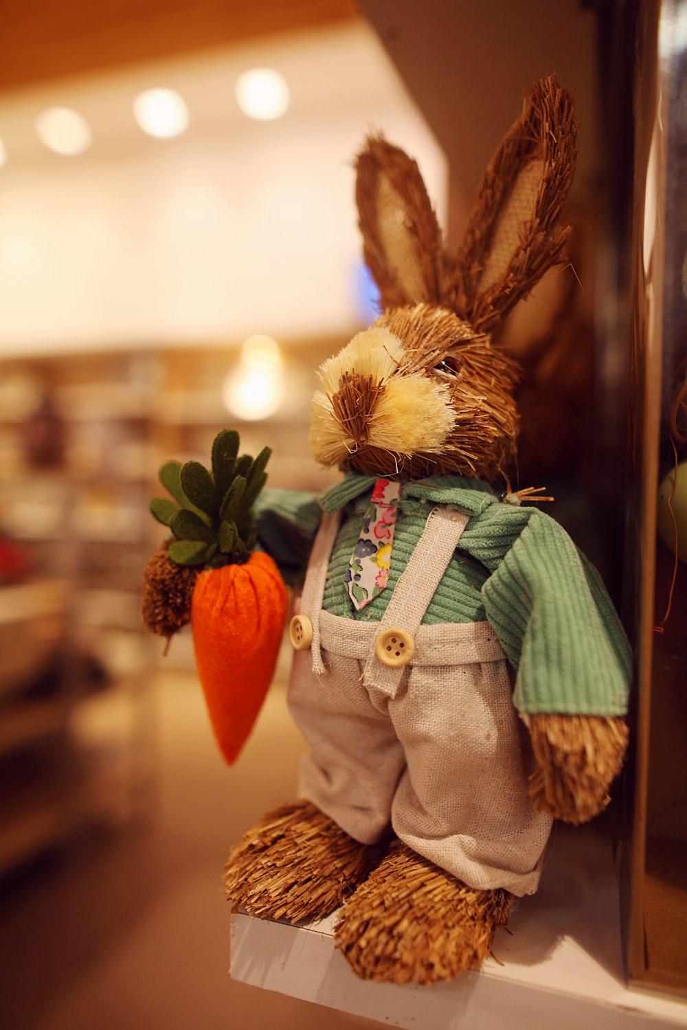 a stuffed rabbit holding a carrot on a shelf