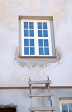 a ladder leaning against a wall with a window above it