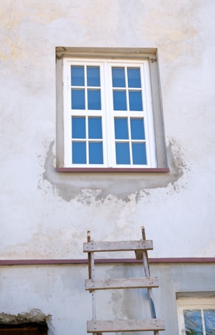 a ladder leaning against a wall with a window above it