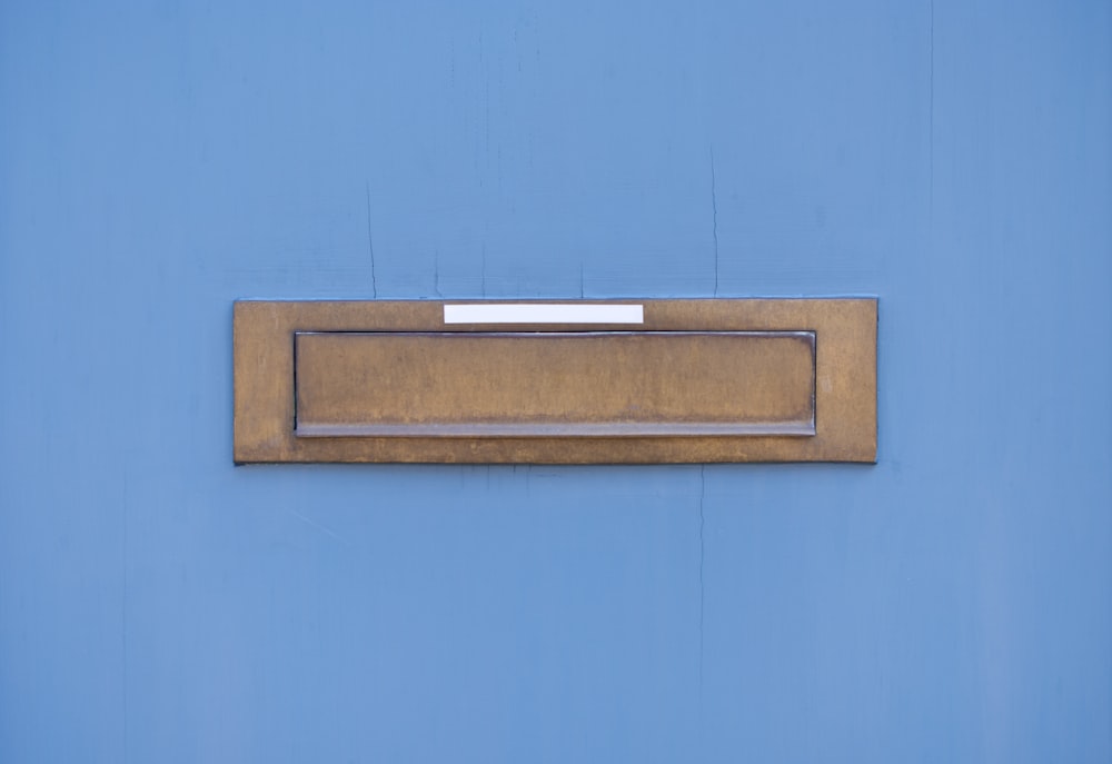 a gold mailbox mounted on a blue wall