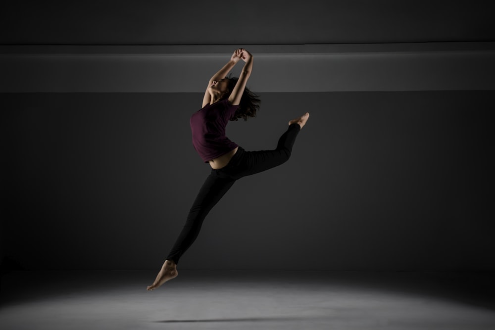 a woman in a purple shirt and black pants is dancing