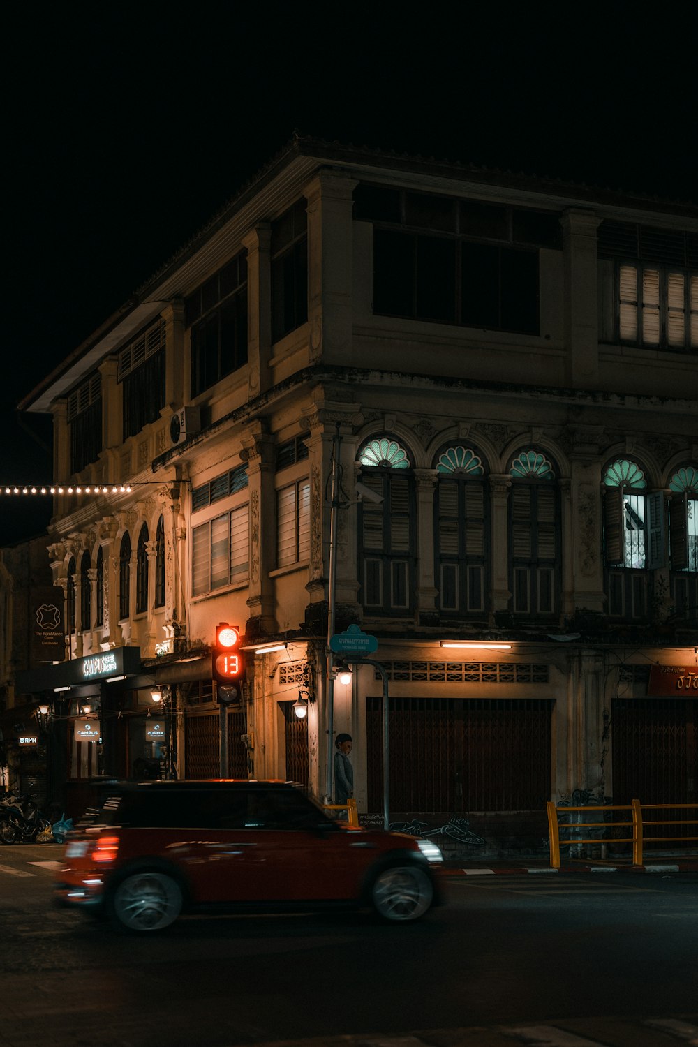 a red car driving down a street at night