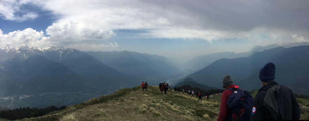 a group of people standing on top of a lush green hillside