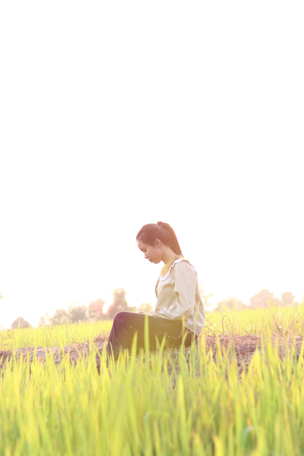 a woman sitting in a field of tall grass