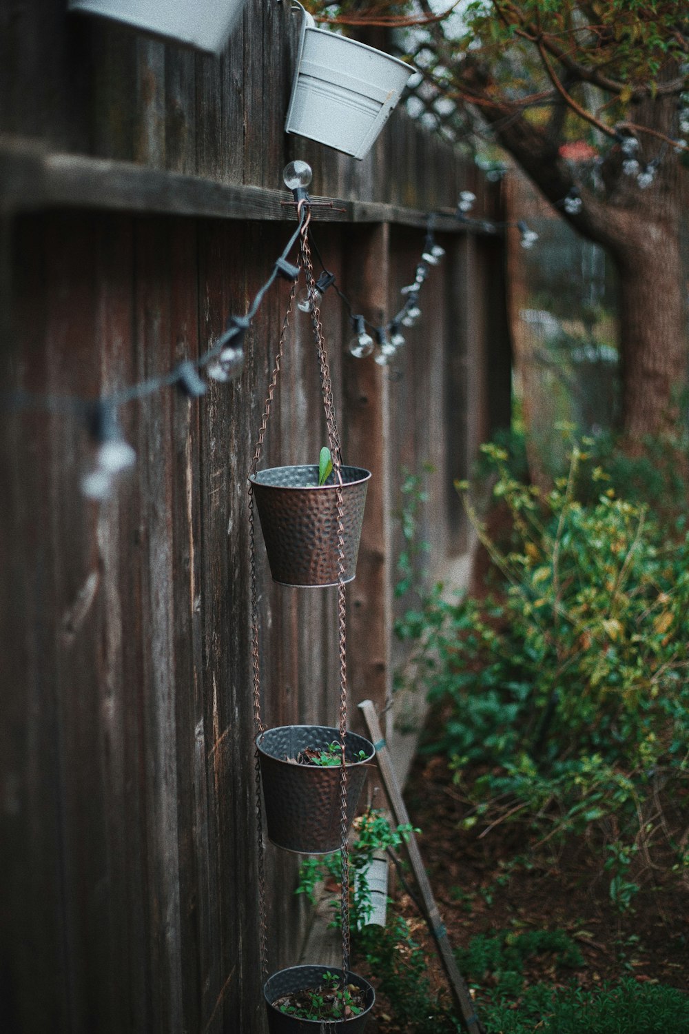 a row of hanging planters on a wooden fence