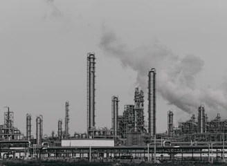 a black and white photo of a factory with smoke stacks
