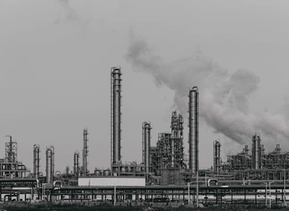 a black and white photo of a factory with smoke stacks