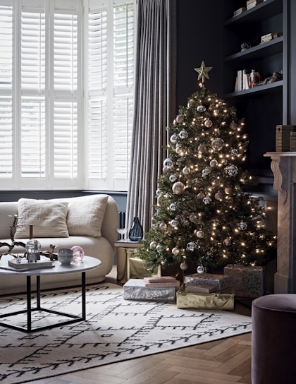 A cozy living room decorated for Christmas with a festive tree.