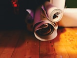 Several rolls of paper are placed on a wooden surface, bathed in warm light. Shadows and highlights create a cozy, vintage atmosphere.