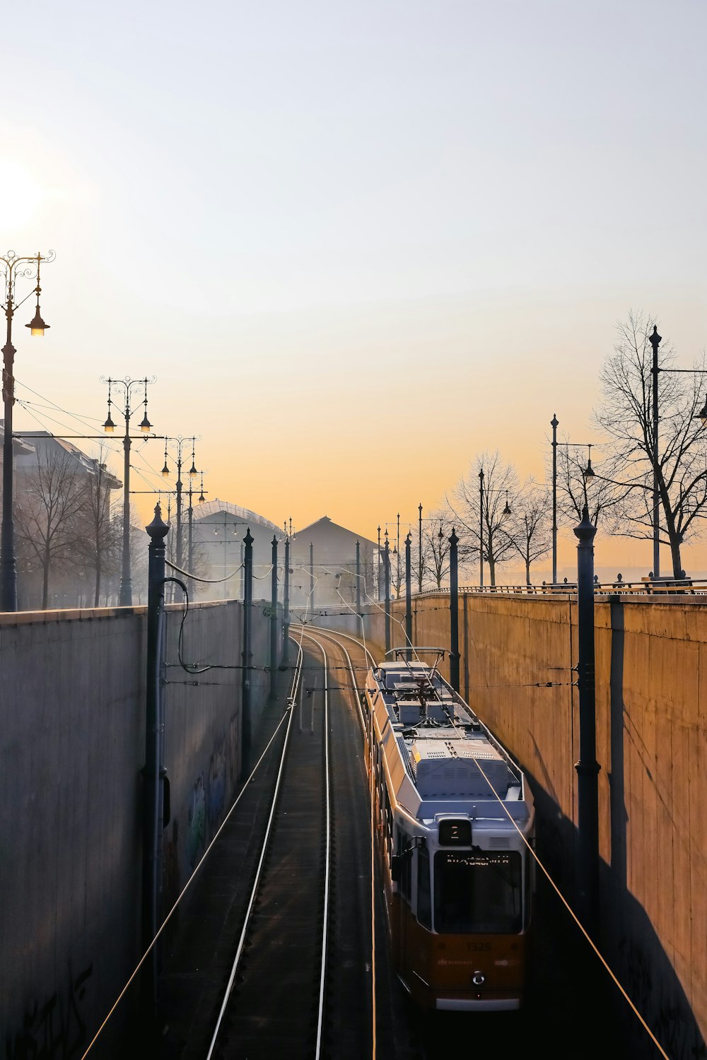 a train traveling down train tracks next to a wall