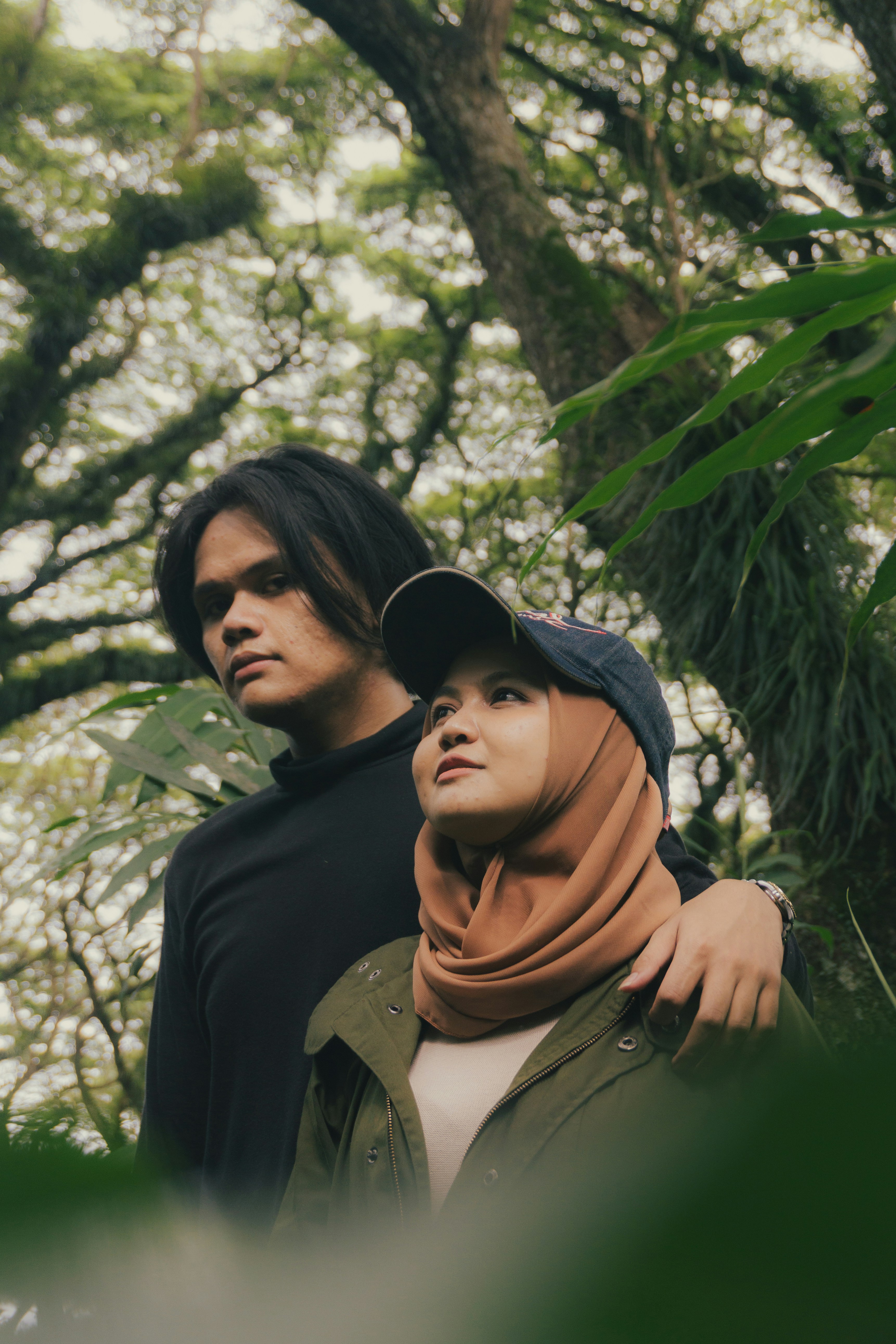 a man and a woman standing next to each other in a forest