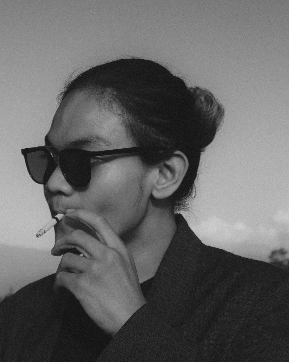a woman wearing sunglasses smoking a cigarette