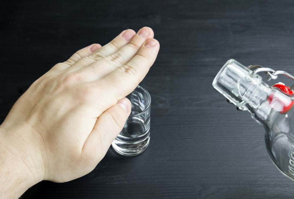 a hand reaching for a glass of water